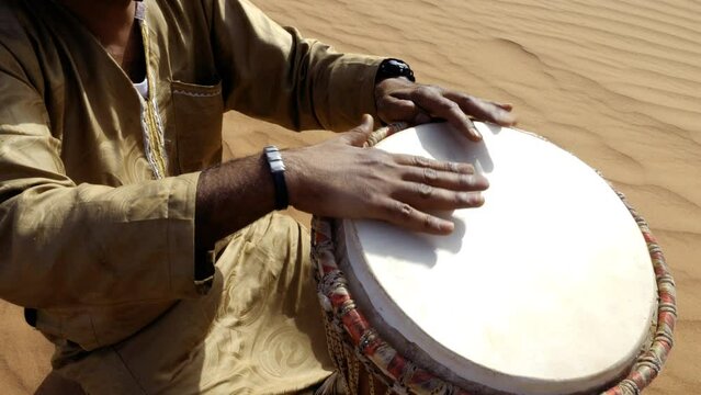 A Moroccan man plays a traditional djembe drum in the desert. Nord-African traditional music is often played in the desert and on festivals. 4k