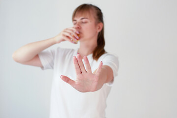 a woman drinks strong alcohol and shows no with her hand. female alcoholism.