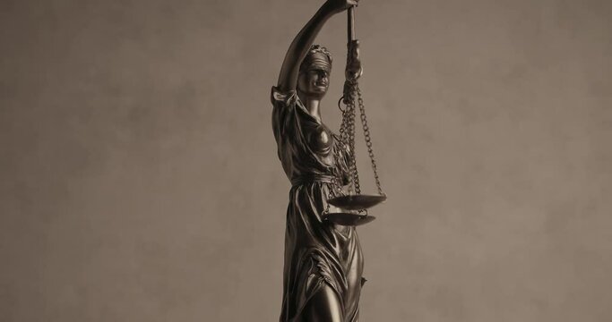 project video of bronze law statue signifying equality and power, justice and balance, holding scale and sword and spinning
