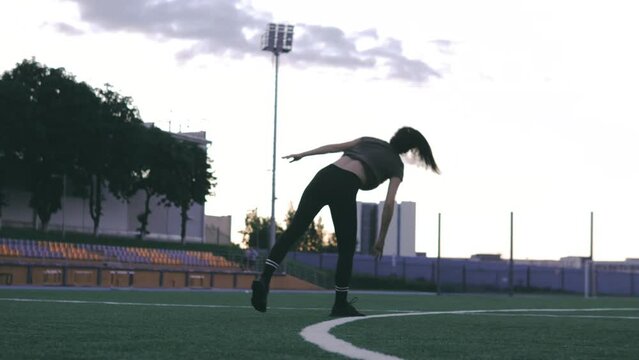 Close up beautiful Caucasian female in sporty clothes practicing wheel gymnastic exercise at the stadium. Yoga concept. Female gymnast at stadium practicing, doing fitness