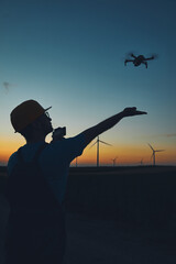 Fototapeta na wymiar Engineer mechanic using drone for inspection in a windmill farm park.