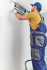 Repairman cleaning and fixing indoors AC unit.