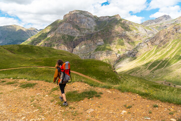 A young woman in the mountain trekking with her son in the backpack in the Ripera valley, Pyrenees