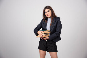 Portrait of young business woman holding a stack of books