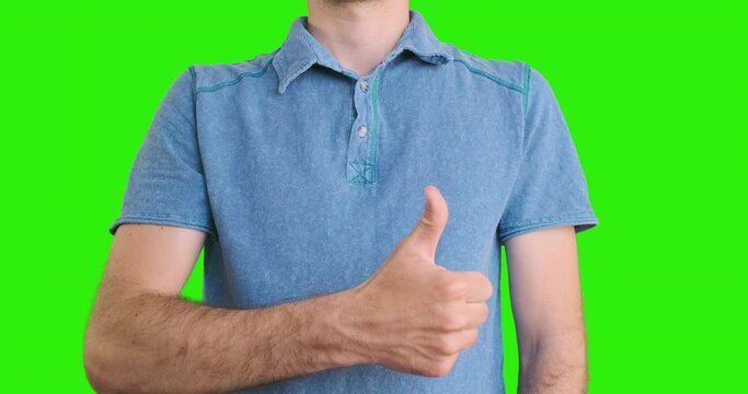 Young man shows thumbs up against background of his chest. Portrait, chroma key, green screen. The concept of getting job, a delivery worker, a guarantee, good service, company, issuing loan.
