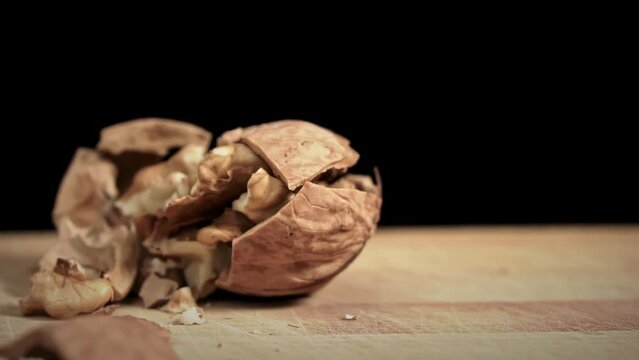 Hammer breaks a walnut in slow mo on a black background. Toughie. Nuts are good for the brain. Heap of walnuts close-up.