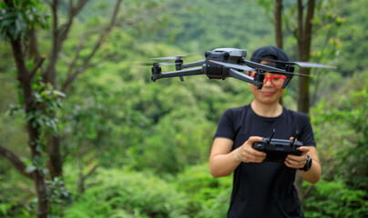People remote control a flying drone in summer forest