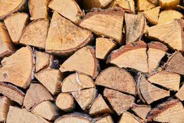 Wood chopped up and stacked into a storage pile. Collecting firewood as a source of energy. Different sizes and shapes of logs after felling, materials for tools and shelter from above