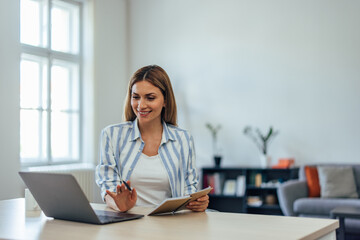 Busy woman having a meeting online, smiling and talking, holding notes.