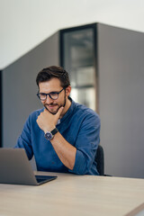 Thoughtful man, holding a hand on his chin, making new plans, using a laptop.