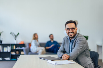 Fototapeta premium Adult businessman holding hands on the desk, smiling for the camera.