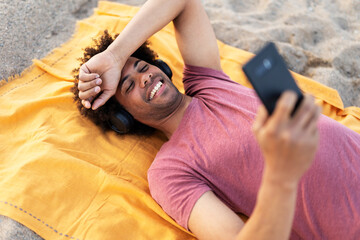 Happy smling man sunbathing on beach towel. Handsome man relaxing at the beach..