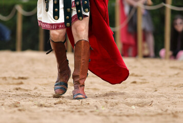 Detail of historical leather boots of a man disguised as a roman walking on sand in the arena....