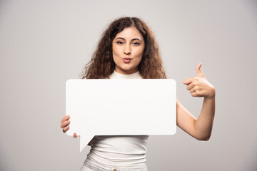 Naklejka premium Young woman holding empty blank white speech poster