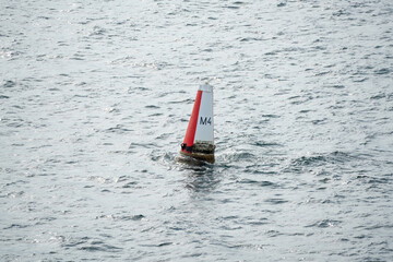 Red and white navigation marker buoy at sea.