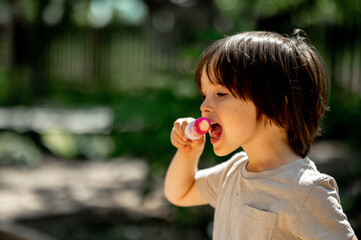 a boy of Asian appearance eats fruit ice, a child eats cold ice cream on a hot summer day while walking in the park