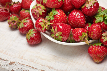 strawberries in a plate on a white wooden background, fresh red berries, concept of fresh fruits and healthy food