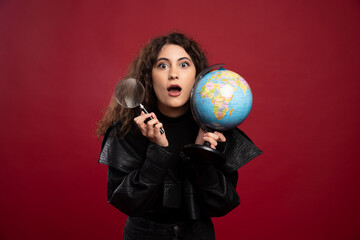 Young woman in all black outfit holding a globe with loupe