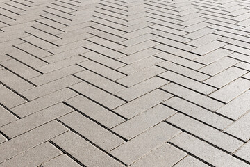 Gray concrete elongated paving stones are laid in the form of parquet. The backlight reveals a...