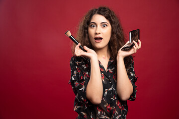 Elegant woman holding makeup brush and bronzer