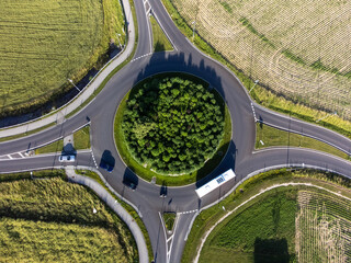 vertical aerial photography of a roundabount with a bus and several cars, drone footage