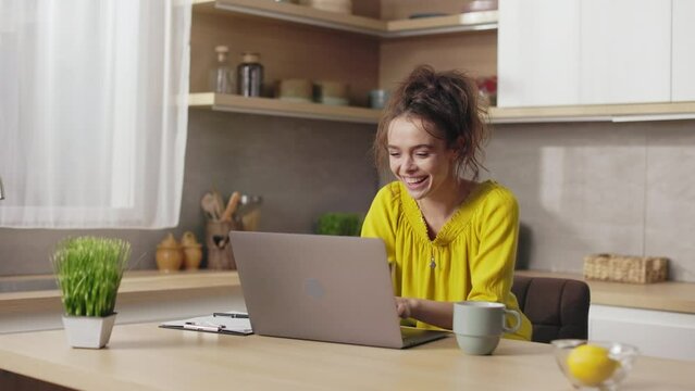 Caucasian young woman gesturing from happiness while reading good news on modern laptop. Joyful female freelance celebrating some success or achievement at work.