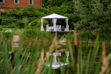 white wedding pavilion altar next to a small lake