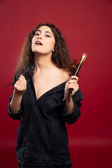 Young artist painting herself on red background