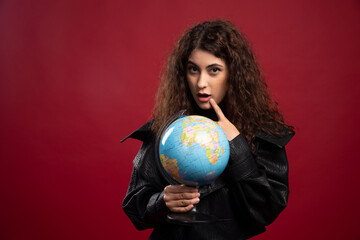 Curly woman holding globe on red background