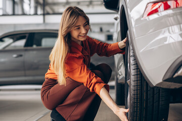 Woman checking tires in a car standing in a car showroom