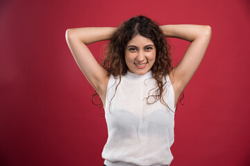 Woman holding hands behind the head on red background