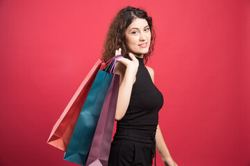 Woman showing her new buying clothes on red background