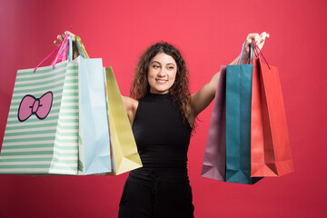 Happy woman with many of bags on red background