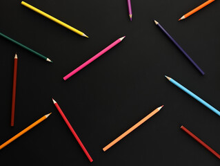 background colored pencils in chaotic order on black background with frame for copy space