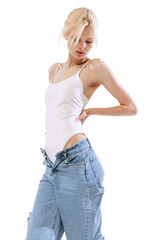 Young tender slender woman wearing oversize jeans posing isolated over white background. Art, beauty, action, flexibility, inspiration concept.