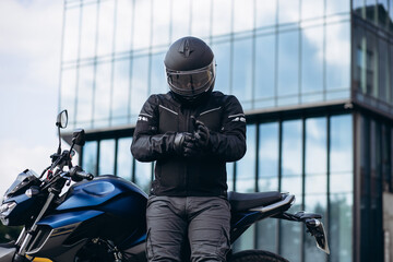 Handsome motorcyclist on his moto riding in the city - obrazy, fototapety, plakaty