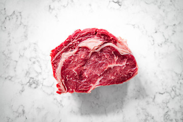 Cut of rib-eye steak on a marble counter top, close-up