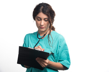 Female doctor with stethoscope writes something in a clipboard on white background