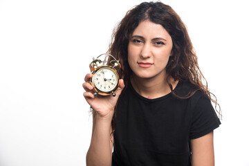 Sleepy woman holding an alarm clock on white background
