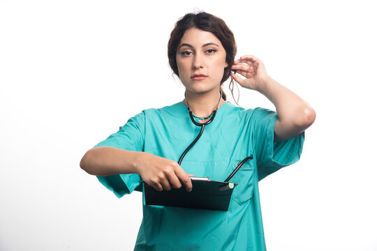 Young woman doctor with stethoscope holding clipboard on white background