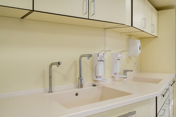 elbow soap and antiseptic dispenser or sanitizer wall mounted for hand disinfection and water tap sink with faucet bathroom or clinic