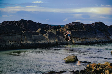 Kids climbing rock wall at The Tanks tourist attraction natural rock pool at Forster, New South...