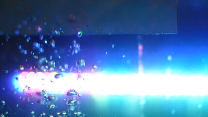 Side view of beautiful chaotic motion of oxygen bubbles, water background. Frame. Empty glass tank with water and bright blue lamp on the background.