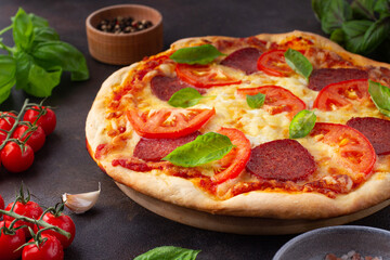 Pizza with tomatoes and basil on the table, close-up
