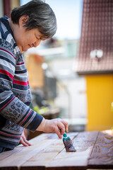 a mentally handicapped or disabled woman glazes several wooden boards