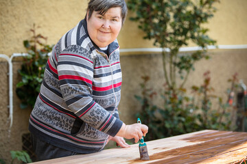 a mentally handicapped or disabled woman glazes several wooden boards