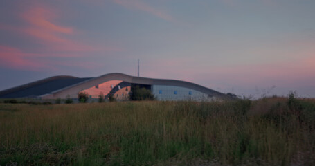 Beautiful grass field landscape grow by big building. Sunset nature background.