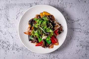 salad of vegetables and fried eggplant. on a light concrete background