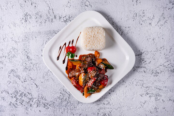meat with vegetables and boiled rice. on a light concrete background