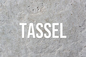 TASSEL - word on concrete background. Cement floor, wall.